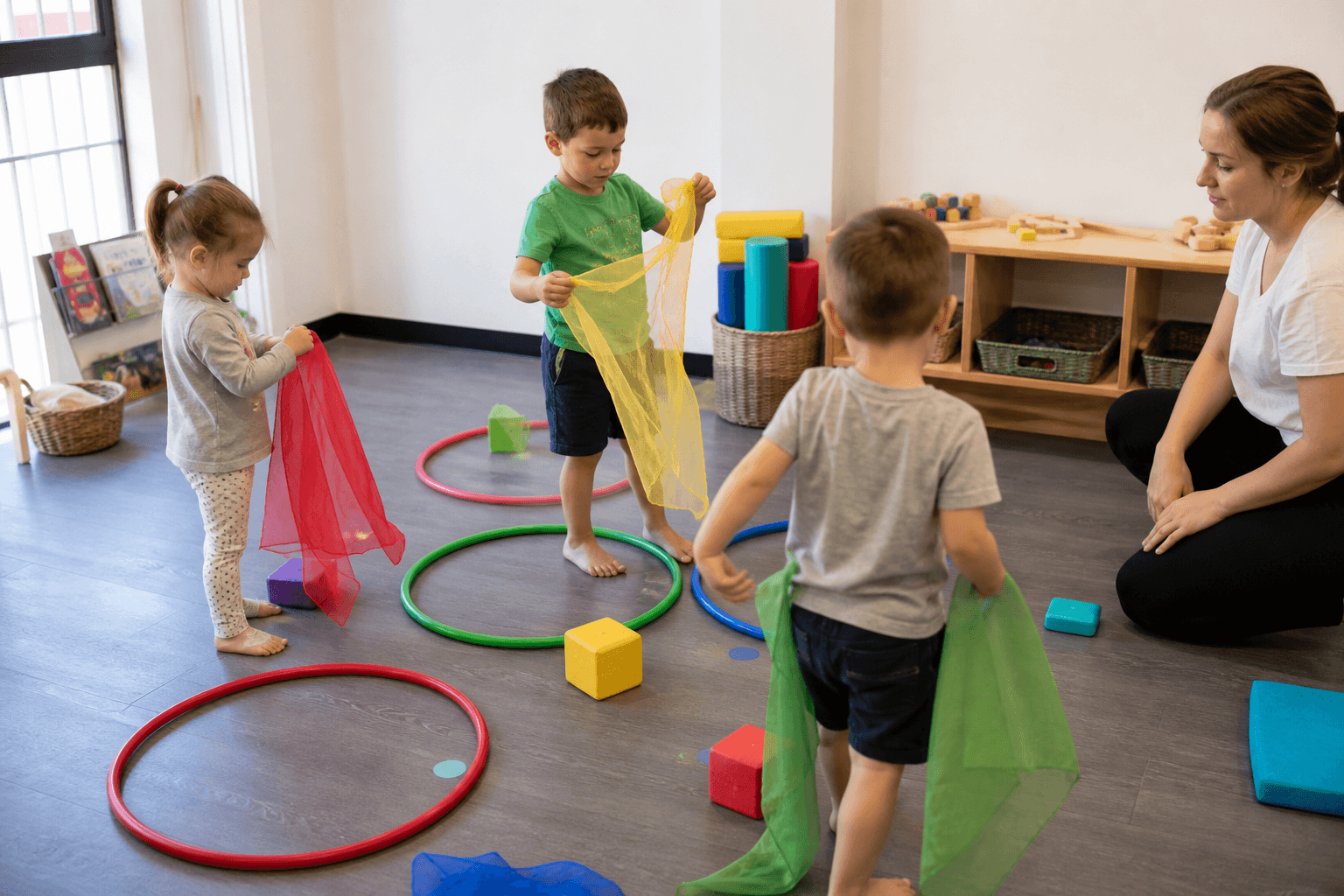 Niños explorando telas aros y bloques en un escenario motor