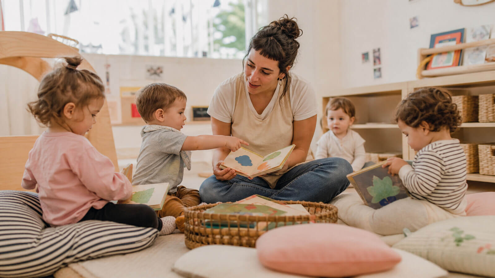Docente compartiendo libros y rimas con bebés y niños de sala de 2